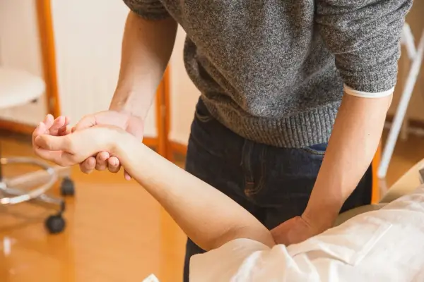 Terapeuta examina la muñeca de un paciente. ¿Puedo ir a trabajar con un esguince de muñeca?