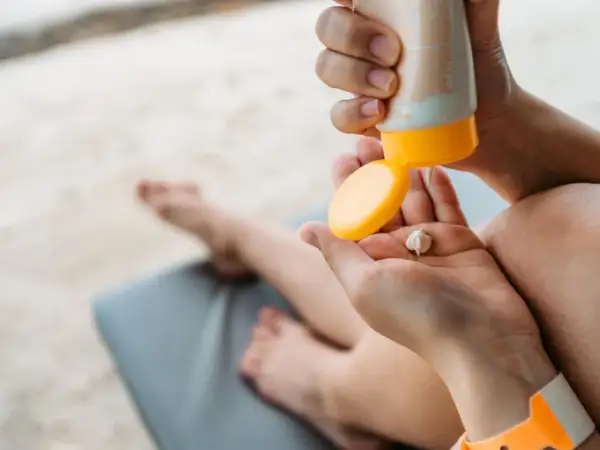 Manos aplicando crema solar en la palma. ¡Revisa la caducidad crema solar antes de usarla para proteger tu piel!