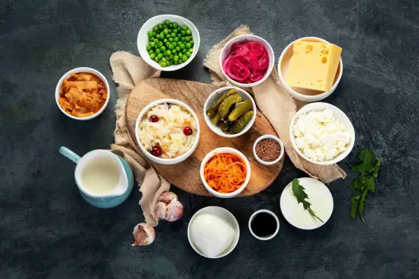 Variedad de 20 alimentos probióticos: kimchi, chucrut, pepinillos, yogur, queso, cebolla morada encurtida, zanahoria rallada, guisantes, ajo, semillas de lino y más.