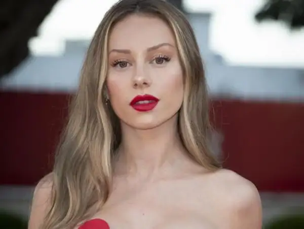 Mujer con labios rojos y cabello largo con mechas rubias naturales que brillan bajo la luz.
